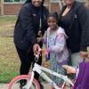 2 adults stand next to girl with new bike