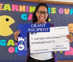 Grant recipient, Tameko Brigham, holds up her GEF check.